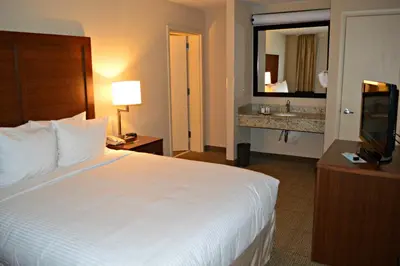 a hotel room with a large white bed and a sink at Wyndham Garden Hotel Cross Lanes Charleston in Charleston