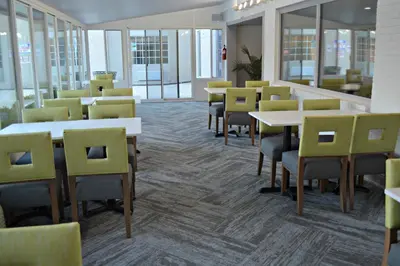a dining room with tables and chairs and windows at Wyndham Garden Hotel Cross Lanes Charleston in Charleston