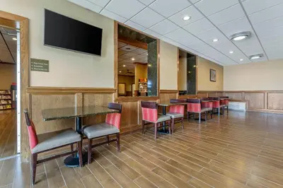 a waiting room with tables and chairs and a flat screen tv at Comfort Inn & Suites Triadelphia - Wheeling in Triadelphia