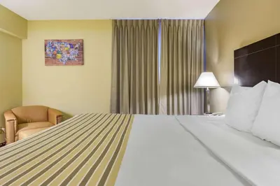 a hotel room with a large bed and a chair at Econo Lodge Inn & Suites Triadelphia - Wheeling in Triadelphia
