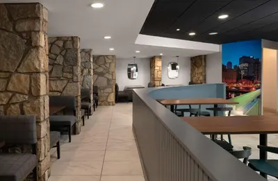 a restaurant with tables and chairs and a stone wall at DoubleTree by Hilton Pittsburgh Airport in Moon Township