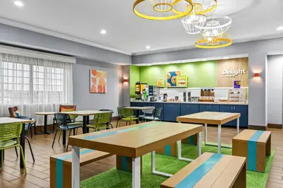 a restaurant with tables and chairs and a cafeteria at Spark by Hilton Cincinnati Fairfield in Forest Park