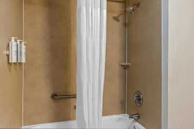 a shower with a white shower curtain in a bathroom at Spark by Hilton Cincinnati Fairfield in Forest Park
