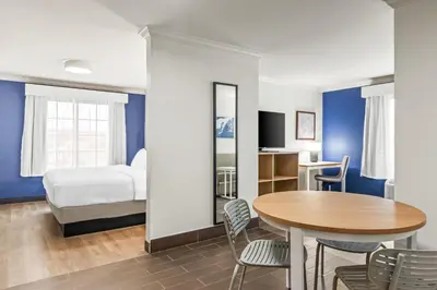 a room with a bed and a table and chairs at Spark by Hilton Cincinnati Fairfield in Forest Park