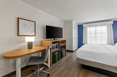 a hotel room with a bed and a desk with a computer at Spark by Hilton Cincinnati Fairfield in Forest Park
