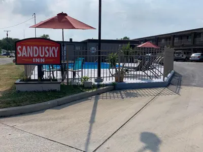 a sign for a sandwich inn with chairs and an umbrella at Sandusky Inn in Sandusky