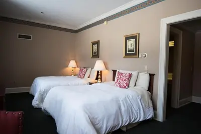 two beds in a hotel room with white sheets at The Bertram Inn at Glenmoor in Canton