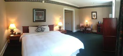a hotel room with a bed and two lamps on tables at The Bertram Inn at Glenmoor in Canton
