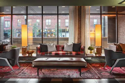 a living room with a couch and chairs and windows at Graduate by Hilton Columbus in Columbus