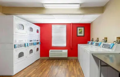 a laundry room with red walls and white appliances at Extended Stay America Suites - Fort Wayne - South in Fort Wayne