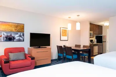 a hotel room with a bed and a dining room at TownePlace Suites Fort Wayne North in Fort Wayne