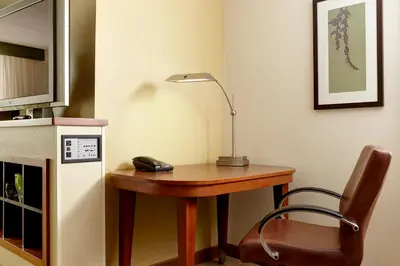 a desk with a lamp and a chair in a room at Hyatt Place Fort Wayne - Northwest in Fort Wayne
