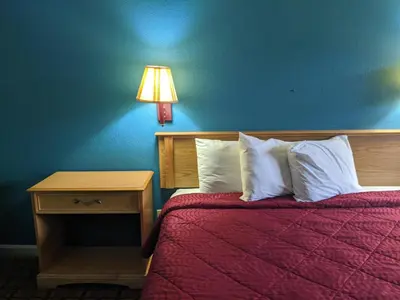 a bedroom with a bed with a red blanket and a lamp at Executive Inn in Fort Wayne