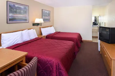 a hotel room with two beds and a flat screen tv at Executive Inn in Fort Wayne