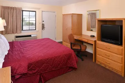 a hotel room with a bed and a desk and a television at Executive Inn in Fort Wayne