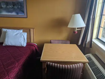 a hotel room with a bed and a table and a lamp at Executive Inn in Fort Wayne