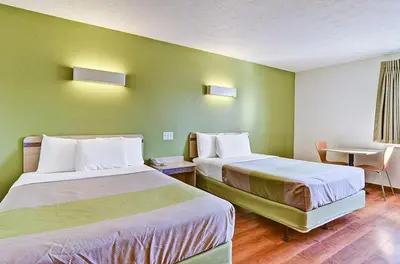 a hotel room with two beds and a table at Economy Inn Pittsburgh Airport in Moon