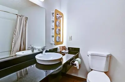 a bathroom with a sink and a toilet and a mirror at Economy Inn Pittsburgh Airport in Moon