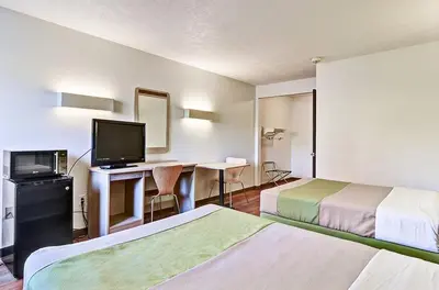 a hotel room with two beds and a desk with a television at Economy Inn Pittsburgh Airport in Moon
