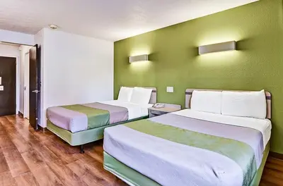 two beds in a room with green walls and wooden floors at Economy Inn Pittsburgh Airport in Moon