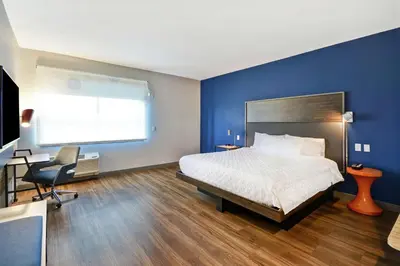 a bedroom with blue walls and a bed and a desk at Tru By Hilton Huber Heights Dayton in Huber Heights