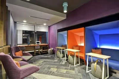 a waiting room with purple walls and tables and chairs at Tru By Hilton Huber Heights Dayton in Huber Heights
