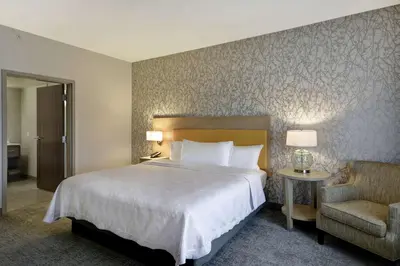 a hotel room with a large bed and a chair at Home2 Suites By Hilton Dayton South in Miamisburg