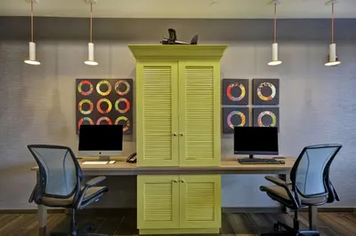 an office with a yellow desk with two computers on it at Home2 Suites By Hilton Dayton South in Miamisburg