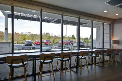 a bar with a row of chairs and windows at Home2 Suites By Hilton Dayton South in Miamisburg