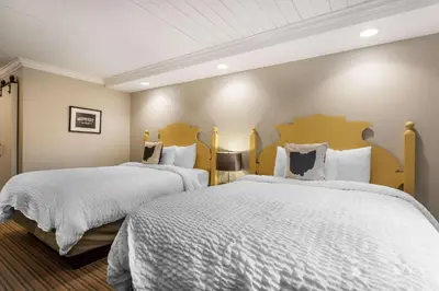 a bedroom with two beds with white sheets at The Aurora Inn Hotel and Event Center in Aurora