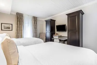 a hotel room with two beds and a television at The Aurora Inn Hotel and Event Center in Aurora