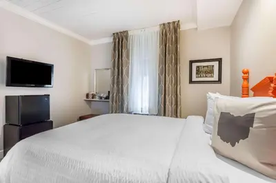 a bedroom with a white bed and a television at The Aurora Inn Hotel and Event Center in Aurora