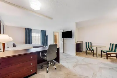 a hotel room with a bed and a desk and chairs at The Blu Hotel Blue Ash Cincinnati, an Ascend Collection Hotel in Blue Ash
