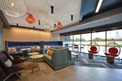 a lobby with couches chairs and tables and windows at Tru By Hilton Mason King's Island in Mason