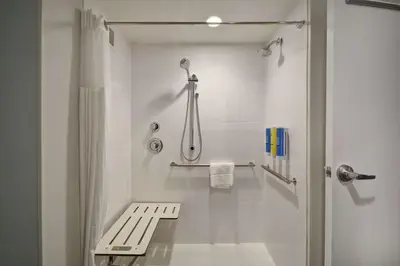 a bathroom with a shower and a bench in it at Tru By Hilton Mason King's Island in Mason