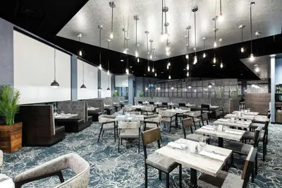 a dining room with tables and chairs and chandeliers at Hilton Garden Inn Pittsburgh Area Beaver Valley, Pa in Monaca