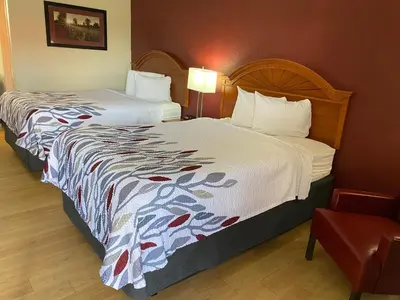 a hotel room with two beds and a chair at Red Roof Inn Wheelersburg in Wheelersburg