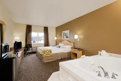 a hotel room with a bed and a bath tub at Baymont by Wyndham Lawrenceburg in Lawrenceburg