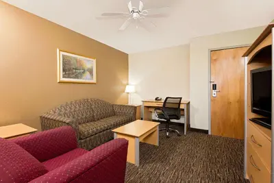 a hotel room with a couch and a table and a desk at Baymont by Wyndham Lawrenceburg in Lawrenceburg
