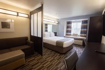 a hotel room with a bed and a couch at Microtel Inn & Suites by Wyndham Waynesburg in Waynesburg