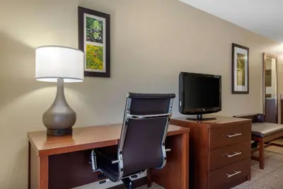 a room with a desk with a television and a chair at Comfort Inn & Suites Northern Kentucky in Wilder