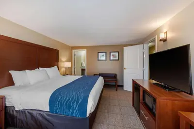a hotel room with a bed and a flat screen tv at Comfort Inn & Suites Northern Kentucky in Wilder