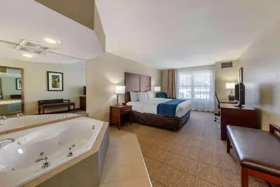a large hotel room with a bed and a tub at Comfort Inn & Suites Northern Kentucky in Wilder