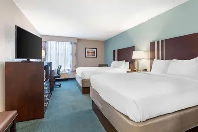 a hotel room with two beds and a flat screen tv at Best Western St. Clairsville Inn & Suites in Saint Clairsville