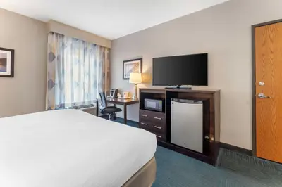 a hotel room with a bed and a flat screen tv at Best Western St. Clairsville Inn & Suites in Saint Clairsville