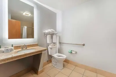 a bathroom with a toilet and a sink and a mirror at Best Western St. Clairsville Inn & Suites in Saint Clairsville
