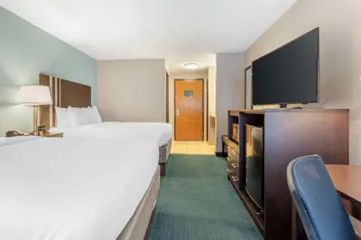 a hotel room with two beds and a flat screen tv at Best Western St. Clairsville Inn & Suites in Saint Clairsville