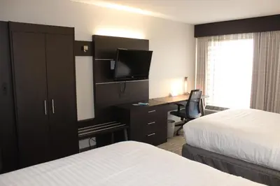 a hotel room with two beds and a desk with a television at Holiday Inn Express & Suites Troy by IHG in Troy