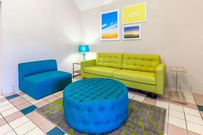a living room with a couch and a blue chair at Days Inn by Wyndham Milan Sandusky South in Milan