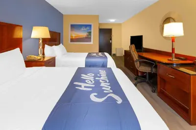 a hotel room with two beds and a desk at Days Inn by Wyndham Milan Sandusky South in Milan